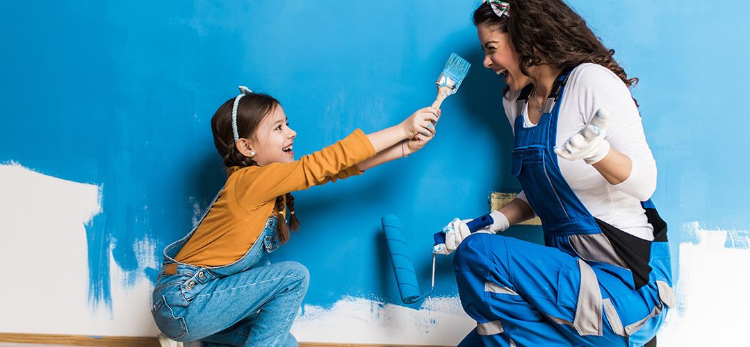 Mother and child having fun painting an interior wall